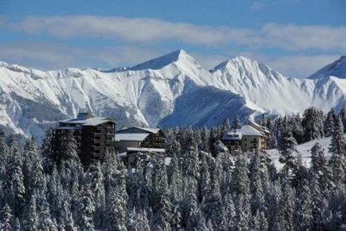 a building on top of a mountain with snow covered mountains at Appartements les Bressanes in Selonnet