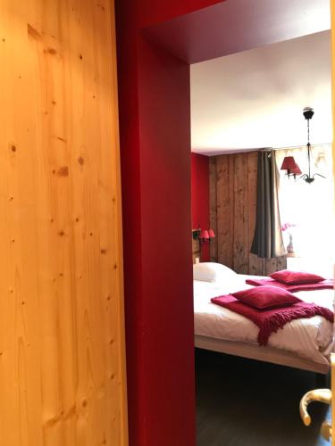 a bedroom with a bed with a red wall at Chez Jeanmyvonne in La Bresse