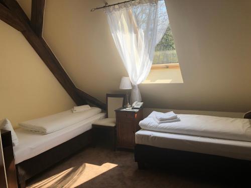 two beds in a room with a window at Pałac Łagów - Hotel in Zgorzelec