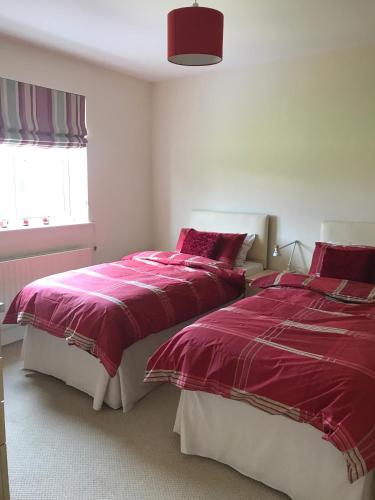 two beds in a bedroom with red and white sheets at Highbury House, Warm and Welcoming. in Darlington