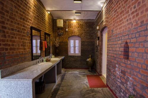 baño con 2 lavabos y pared de ladrillo en Naurang Yatri Niwas en Garli