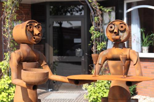 two statues of two people holding a skateboard at Hotel Novum in Hinte