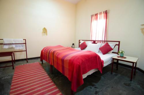a bedroom with a bed with a red blanket and a window at Naurang Yatri Niwas in Garli