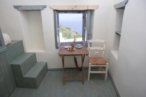 einen kleinen Tisch und einen Stuhl in einem Zimmer mit Fenster in der Unterkunft Pyrgos Stone House in Emporeiós