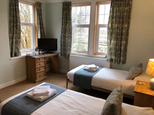 a room with two beds and a television and windows at Tigh na Cheo in Kinlochleven