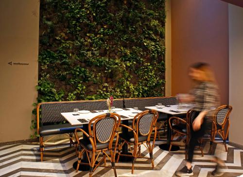 a woman walking past a table in a restaurant at Hotel Lozenge in Athens