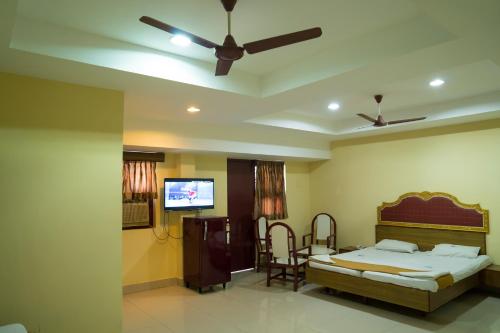 a bedroom with a bed and a flat screen tv at Hotel Chanma International in Coimbatore
