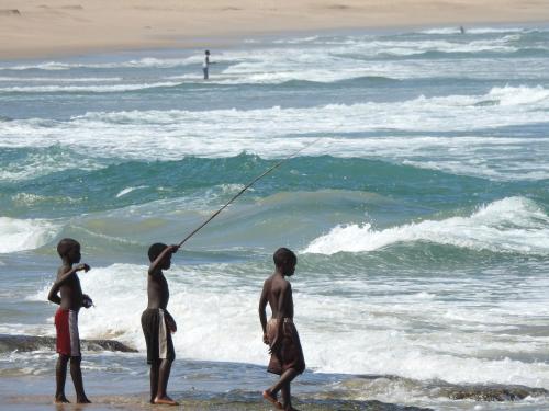a group of boys standing on the beach near the ocean at Naara Eco Lodge & Spa in Chidenguele