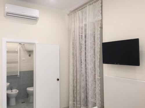 a bathroom with a toilet and a television on a wall at Albergo Oasi in Naples