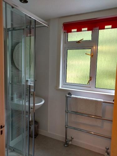 a bathroom with a shower and a sink and a window at Ardlair Guest House in Ullapool
