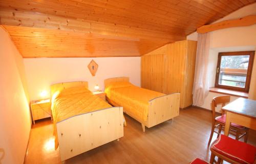 two beds in a room with wooden ceilings at Casa Katia in Canale dʼAgordo