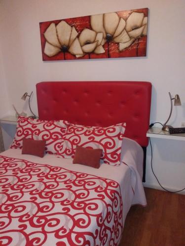 Una cama roja con cabecero rojo en un dormitorio en Apartamento Baykus en Córdoba