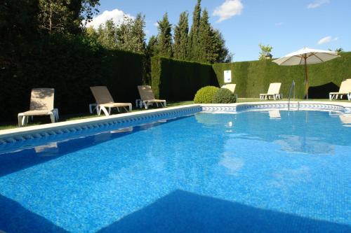 a large swimming pool with chairs and an umbrella at Ad Hoc Parque in Bétera
