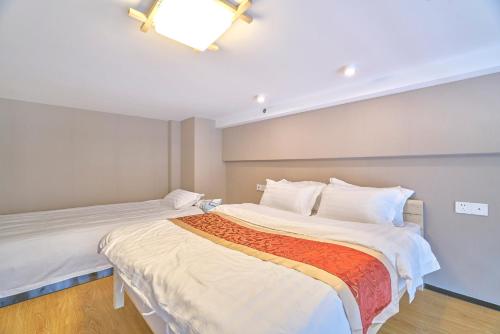a bedroom with two beds with white sheets and an orange blanket at Plesant Daily Rental Apartment in Hangzhou