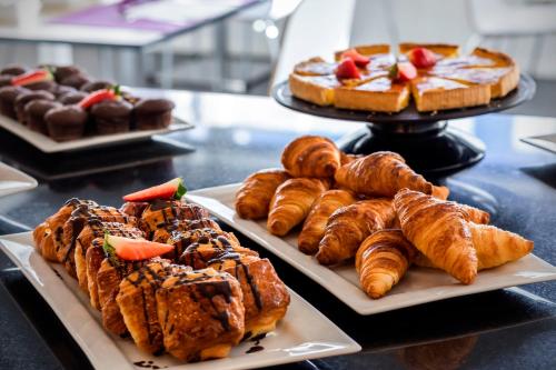 a bunch of pastries on plates on a table at Hotel Zentral Castellana Norte in Madrid