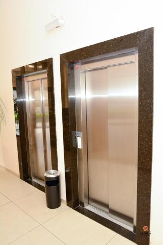 two silver elevators in a building with a trash can at Hotel Maruá in São José dos Campos
