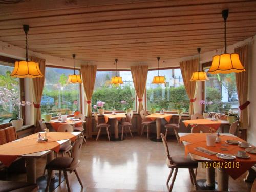 ein Restaurant mit Holztischen, Stühlen und Fenstern in der Unterkunft Pension Unterstein in Schönau am Königssee