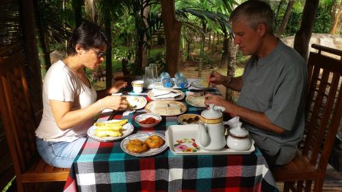 a man and woman sitting at a table with food at Serenity Sigiri Resort in Sigiriya