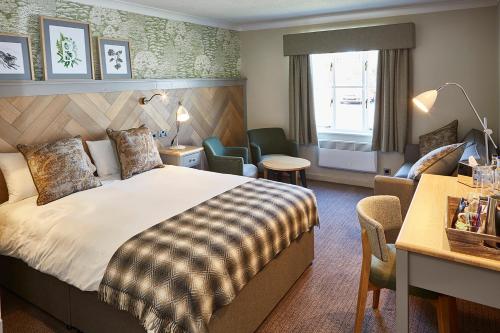 a hotel room with a bed and a desk and chairs at The Bluebird Inn at Samlesbury in Preston