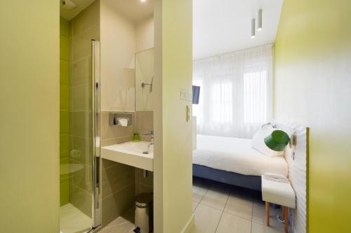 a bathroom with a bed and a sink and a shower at Hôtel Les Voiles in Toulon