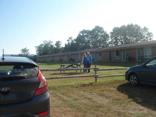two people are standing in front of a building at Motel la Maison de Travers in Baie-Sainte-Catherine