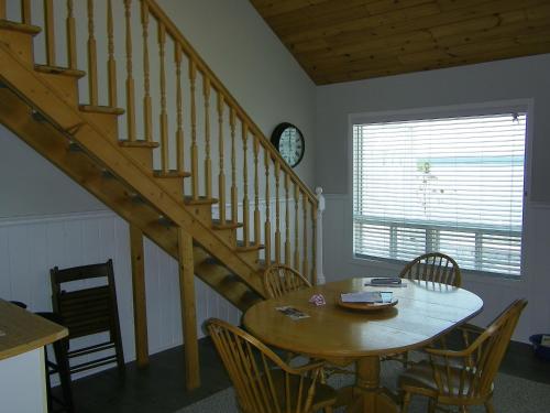 a dining room with a wooden table and a staircase at Sands on Golden Lake in Golden Lake