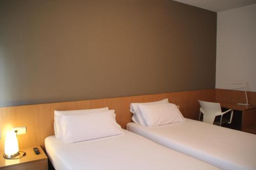 
a hotel room with two beds and two lamps at Hostal Abodi in Pamplona
