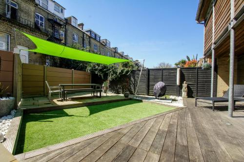 a patio with a bench and a green umbrella at The Edge - Parking - by Brighton Holiday Lets in Brighton & Hove