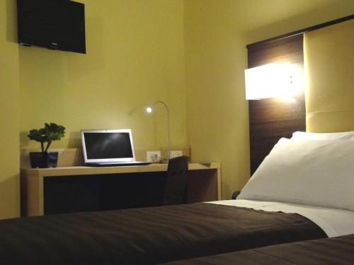 a bedroom with a bed and a desk with a laptop at Hotel Alverì in Mestre