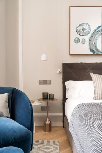 a bedroom with a bed and a blue chair at Lasala Plaza Hotel - Adults Only in Donostia-San Sebastián
