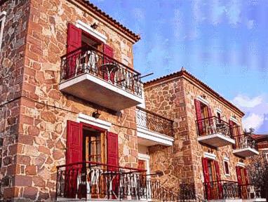 a large brick building with red doors and balconies at The Schoolmistress With The Golden Eyes, studios & rooms in Mythimna