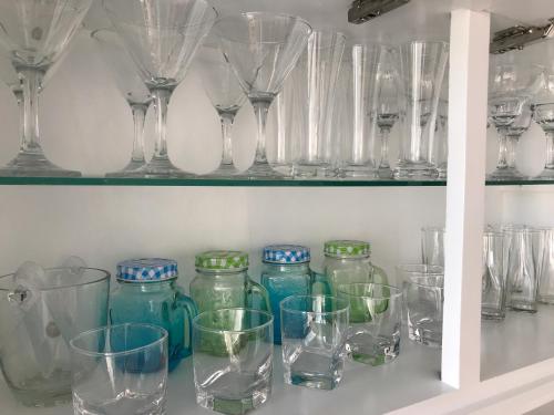 a bunch of glasses and wine glasses on a shelf at Araliya OceanFront Condos Nilaveli, Trincomalee in Nilaveli