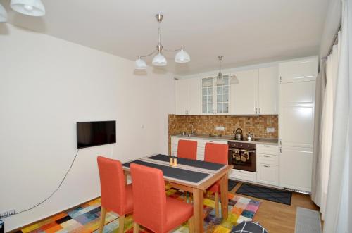 een keuken met een tafel en stoelen en een keuken met witte kasten bij Apartman Mozartova in Praag