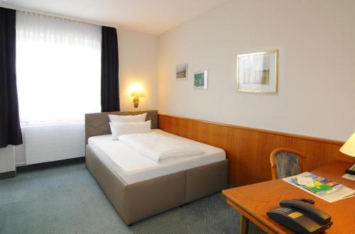 a hotel room with a bed and a desk with a phone at Gasthof-Hotel Maintal in Bad Staffelstein