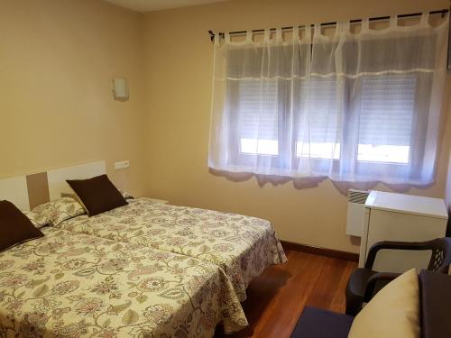 a bedroom with a bed and a window at Hostal Arenal in San Vicente de la Barquera