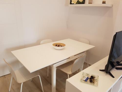 a white dining room table with a tv and a bowl on it at Apartamentos Villajovita in Ceuta