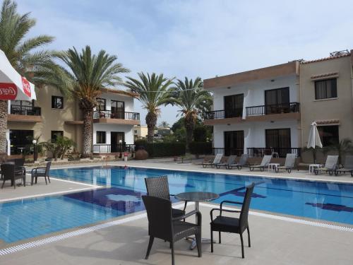 uma piscina com cadeiras e uma mesa em frente a um hotel em Anna Hotel Apartments em Pafos