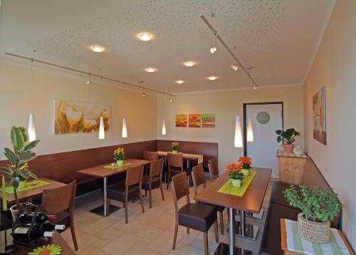 a restaurant with wooden tables and chairs and plants at Hotel Haus am Berg in Trier