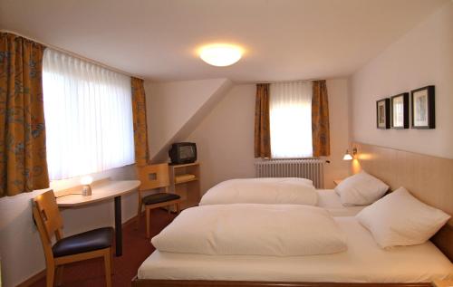 um quarto de hotel com duas camas e uma mesa e uma secretária em Hotel Haus am Berg em Trier