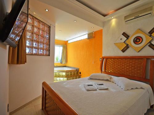 1 dormitorio con 1 cama con paredes de color naranja y ventana en Nice penthouse with pool, close to the beach en Río de Janeiro
