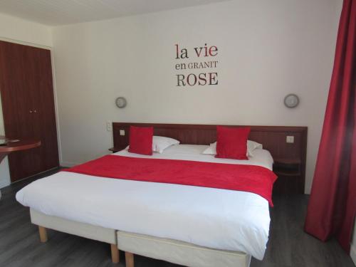 een slaapkamer met een groot wit bed met rode kussens bij Citotel Les Sternes in Perros-Guirec