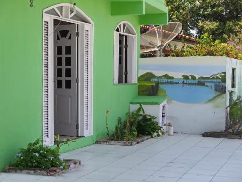 a green house with a door and a wall with a painting at Pousada Rio Alegre in Santo Amaro