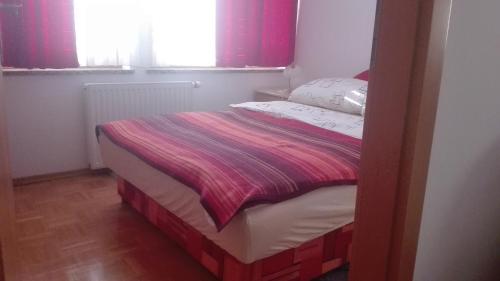 a small bed in a room with red curtains at Apartma Tim Mušič in Črnomelj