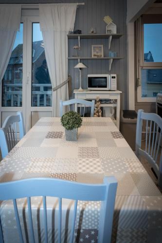 - une table à manger avec une plante au-dessus dans l'établissement Le Galet de Mers, à Mers-les-Bains