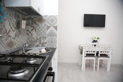 a kitchen with a stove and a sink and a table at La dimora di Clara in Trapani