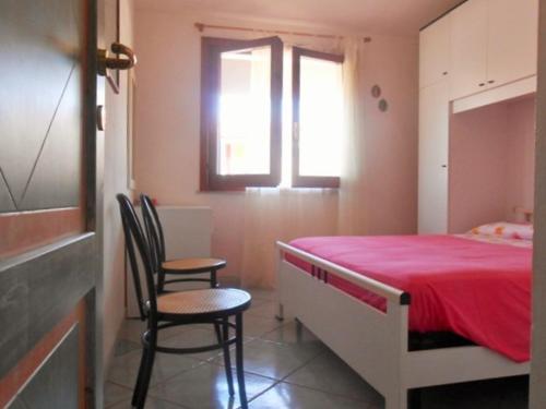 a bedroom with a bed with a red blanket and two chairs at Casa Relax in Villasimius