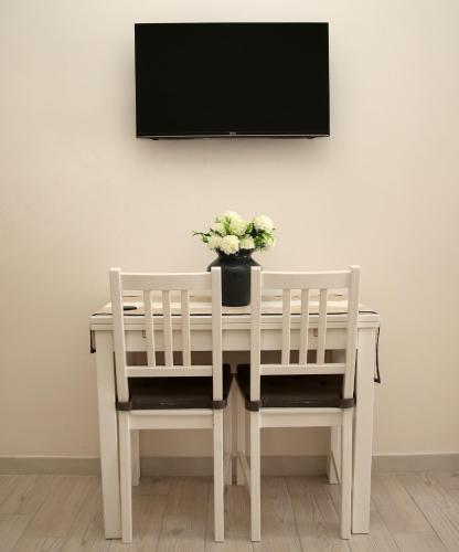 a white table with two chairs and a vase of flowers at La dimora di Clara in Trapani