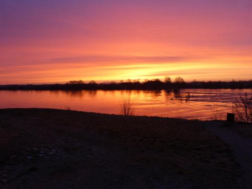 a sunset over a body of water with the sun setting at Hôtel Le Relais Louis XI in Meung-sur-Loire