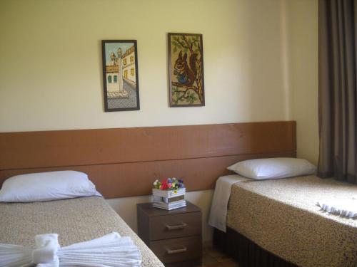 a hotel room with two beds and paintings on the wall at Pousada Chácara Mamma Gaia in Foz do Iguaçu