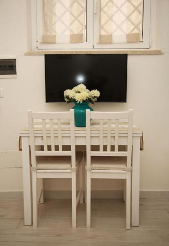 a white table with two chairs and a vase of flowers at La dimora di Clara in Trapani